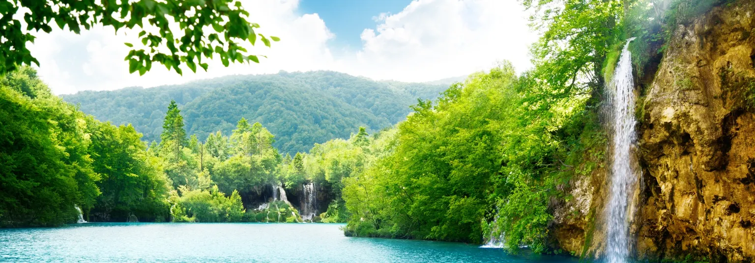 Wasserfall am Plitvicer Seen Nationalpark mit türkisfarbenem See und dichter grüner Landschaft