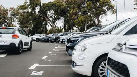 Mehrere Mietwagen stehen geordnet auf einem Parkplatz im Freien
