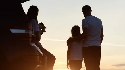 Familie mit Hund schaut dem Sonnenuntergang zu
