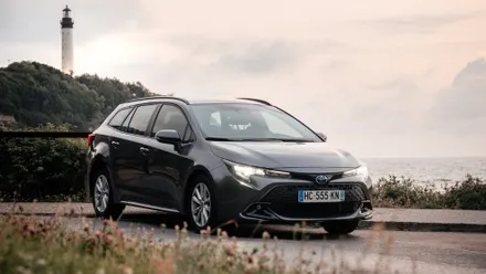 Mietwagen an der französischen Atlantikküste auf Küstenstraße mit Leuchtturm im Hintergrund