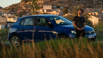 Blauer Mietwagen vor Felsenlandschaft bei Sonnenuntergang, parkend am Rand eines spanischen Dorfes