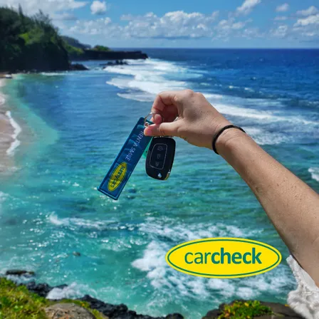 Mietwagen-Schlüssel von Sunny Cars mit Blick auf das Meer während einer Urlaubsreise