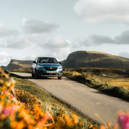 Mietwagen auf einer ruhigen Landstraße in den schottischen Highlands bei sonnigem Wetter