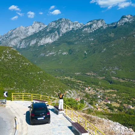 Panoramablick über ein Bergtal in Albanien mit Aussichtspunkt und Mietwagen