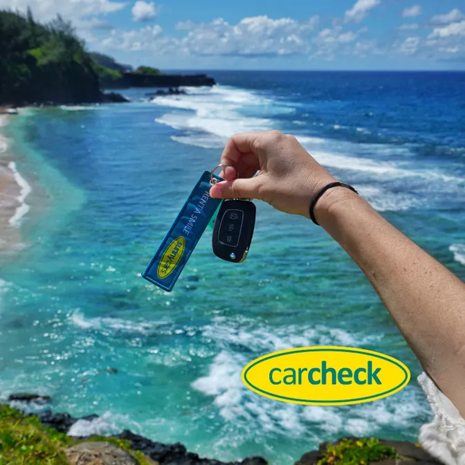 Mietwagen-Schlüssel von Sunny Cars mit Blick auf das Meer während einer Urlaubsreise