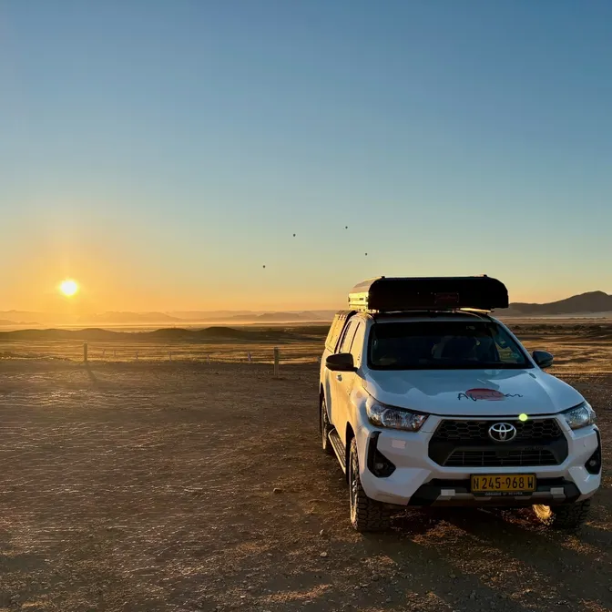 Mietwagen mit Dachzelt parkt im Sonnenuntergang