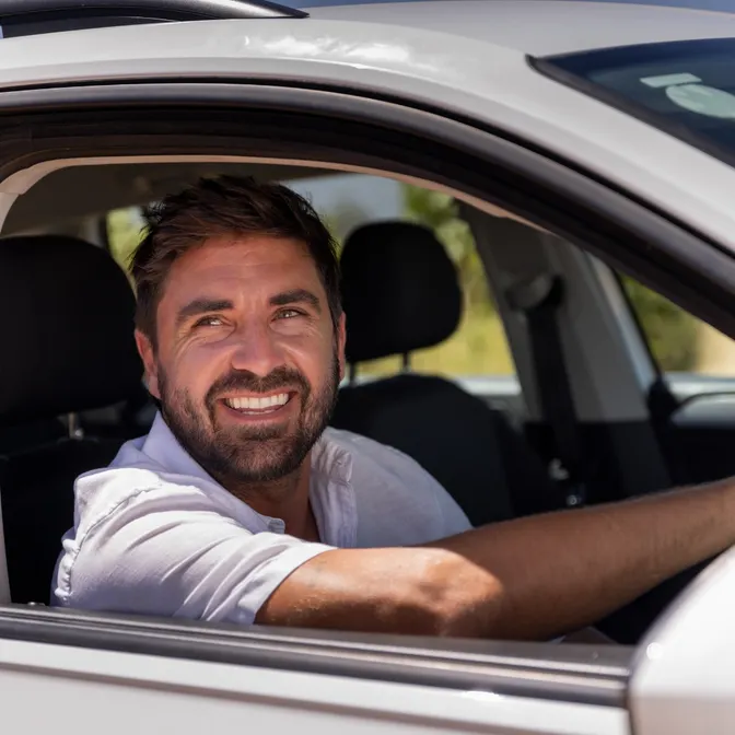 Mann sitzt lächelnd im Auto