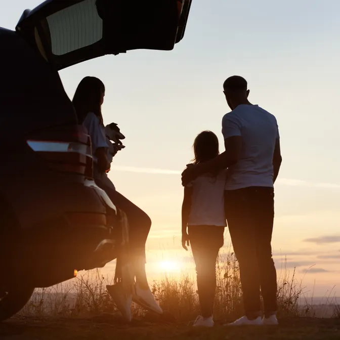 Familie mit Hund schaut Sonnenuntergang zu