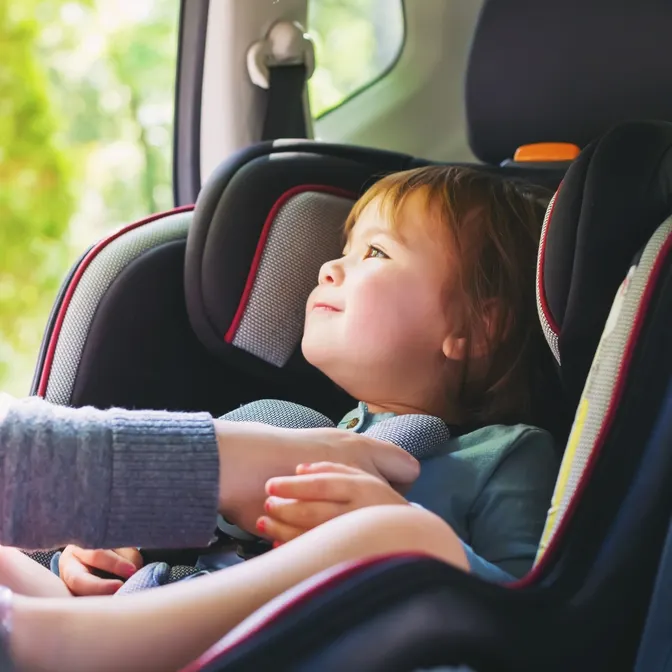 Kleinkind wird im Mietwagen im Kindersitz festgemacht