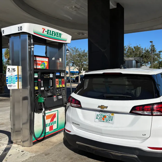 Weißes Auto steht an einer Zapfsäule einer 7-Eleven-Tankstelle