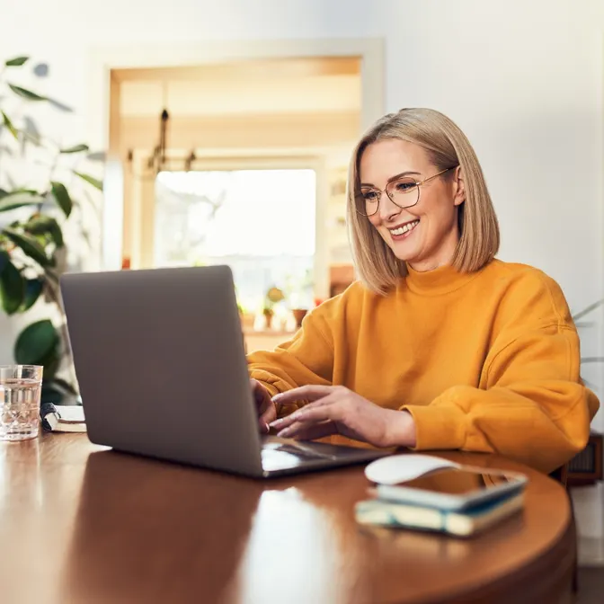 Frau sitzt lächelnd vor dem Laptop