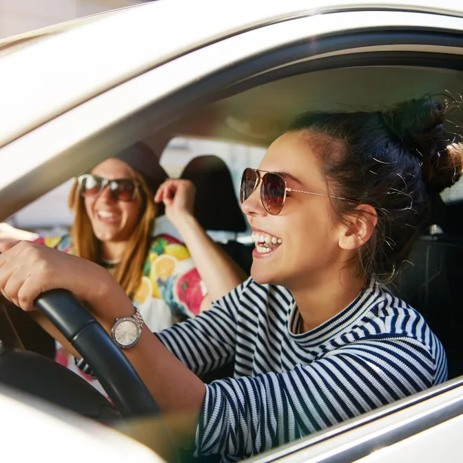 Zwei glückliche Frauen sitzen in einem Mietwagen von Sunny Cars
